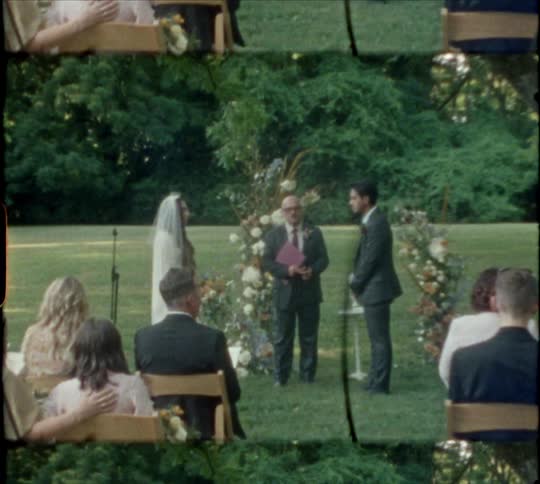 A man with a suit and a woman with a wedding dress standing in a grassy field getting married with trees in the background