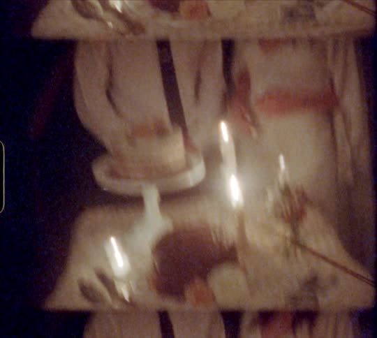 A newly married husband and wife stand behind a table with their wedding cake on it