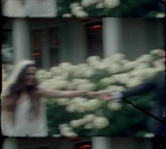 An old film or video of a bride spinning around as she dances with her husband and then he kisses her