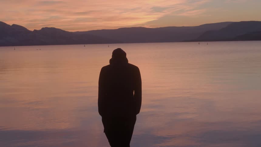 A man is stepping in a lake at sunset