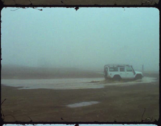 Vehicle drives through shallow water on heavily fogged day