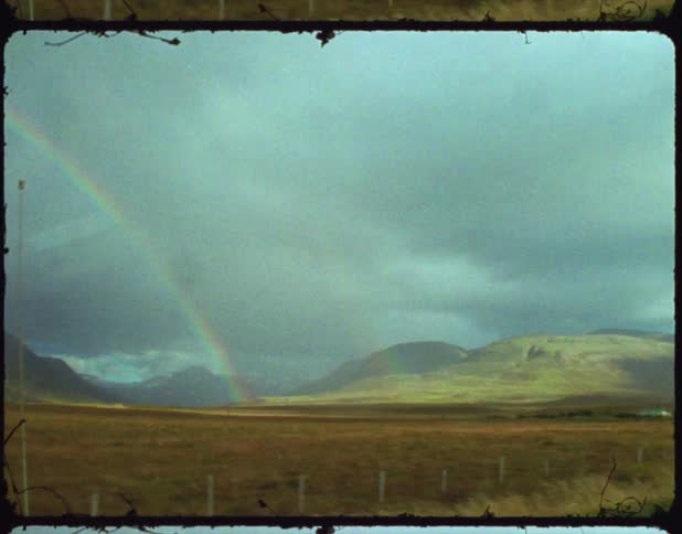 A vintage film of a rainbow over a field