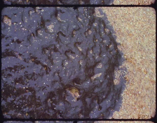 Coarse yellow sand washing over black rocks in the coast on film