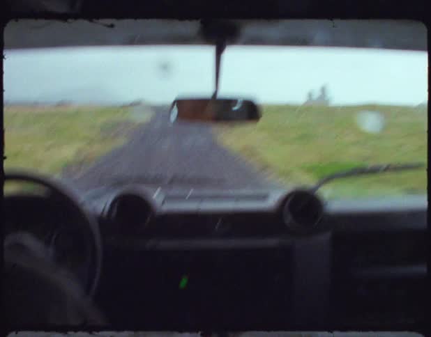 Person driving a vehicle down a dirt road in rural area