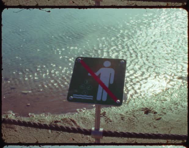 Wind blows across water and a sign rests on a rope nearby