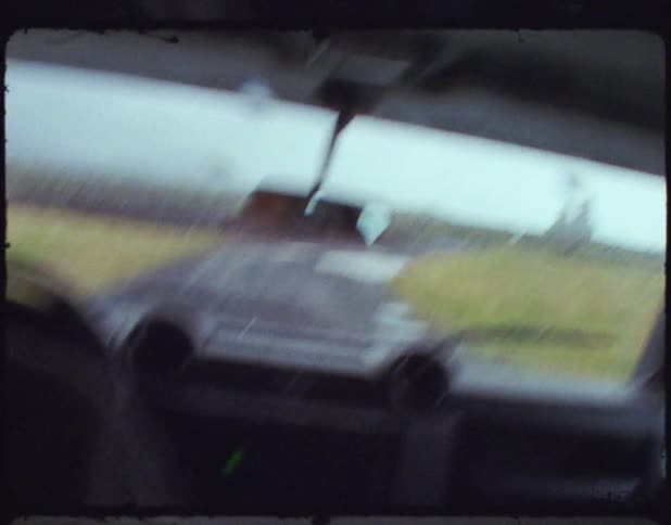 Handheld footage of an all terrain vehicle drivingo on a rural dirt road through a field