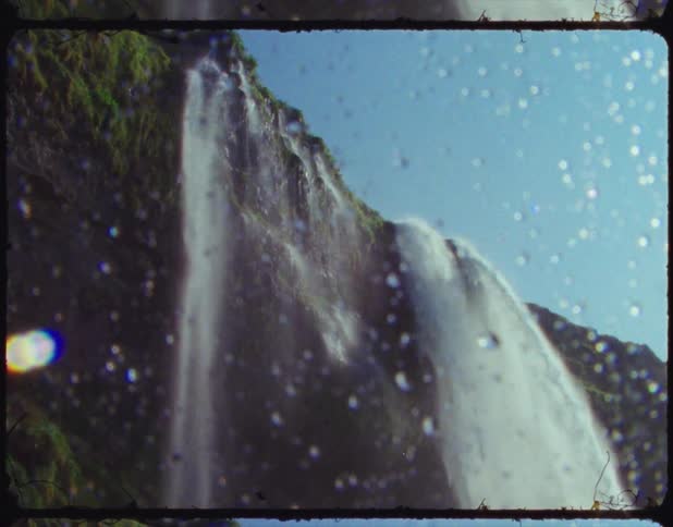 A large waterfall send torrents of water over the side of a cliff under a clear blue sky