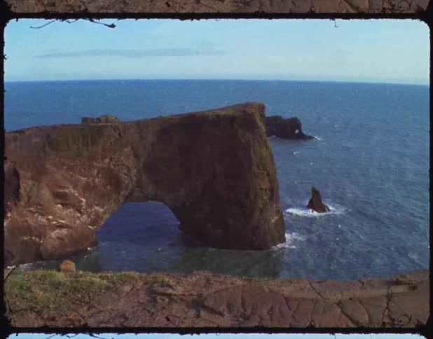 Arched promontory over the waters on the coast of a beach on film
