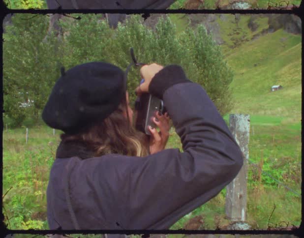 A vintage film of a woman taking a picture of the countryside