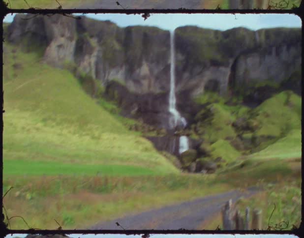 Woman filming a waterfall in the mountains using a film camera