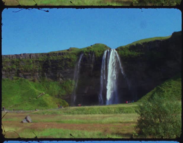 People stand on edge viewing waterfall on opposite side