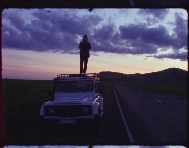 An old film of a person standing on top of her vehicle