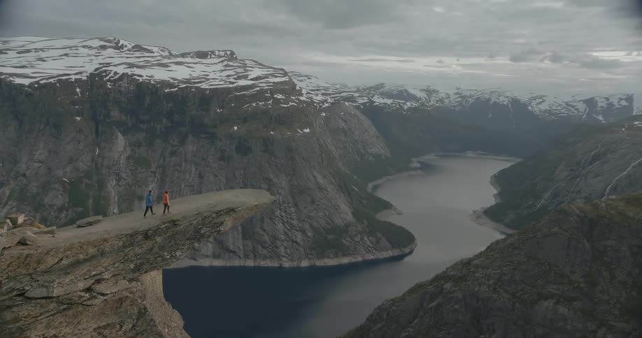 Aerial view of two people walking to the edge of a cliff