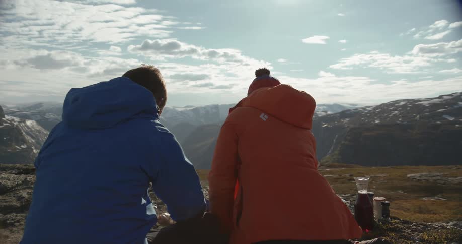 A man and woman eat on a rocky hill