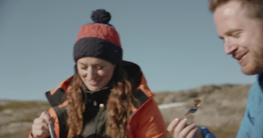 A man and woman eat outside on a cold day