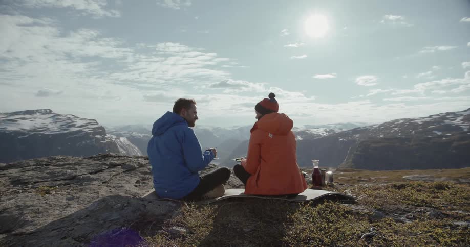 Two people have a picnic on top of a mountain