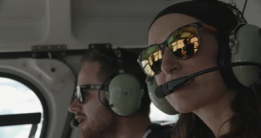 A man and women wearing sunglasses are sitting in an aircraft cabin looking around
