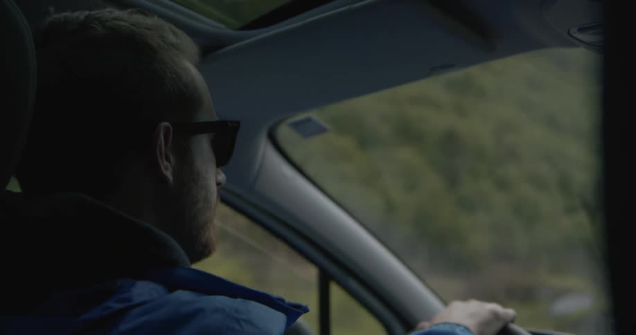 A man wearing sunglasses is driving a car