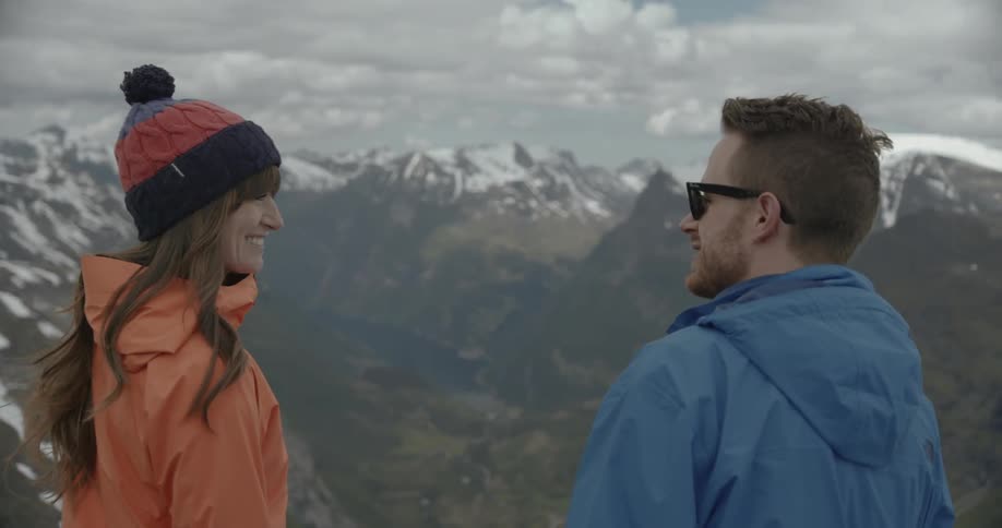 A man and woman talk before a mountain range
