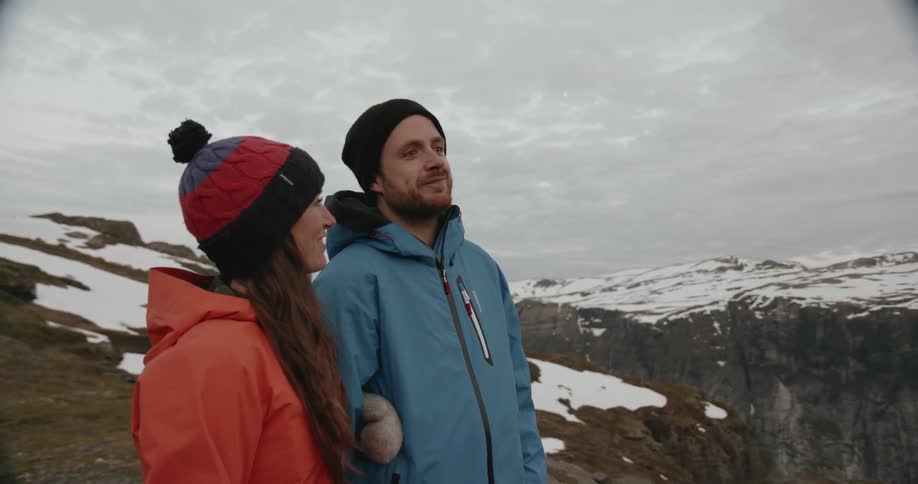 A man and women talk as they stand on a mountain