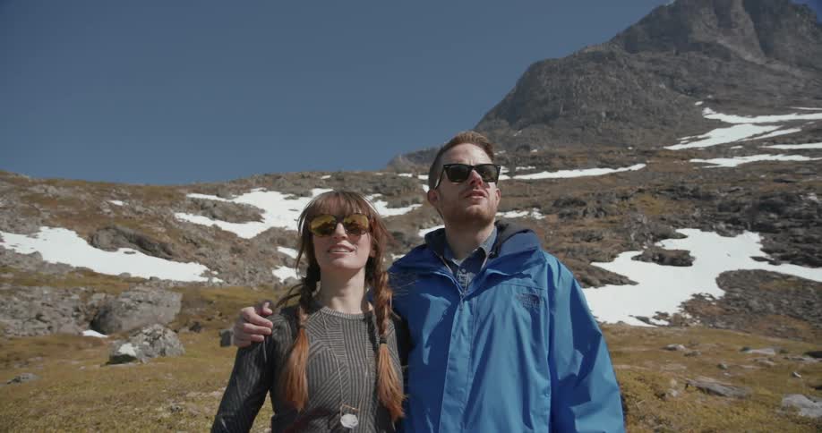 A man and women wearing sunglasses take in a view