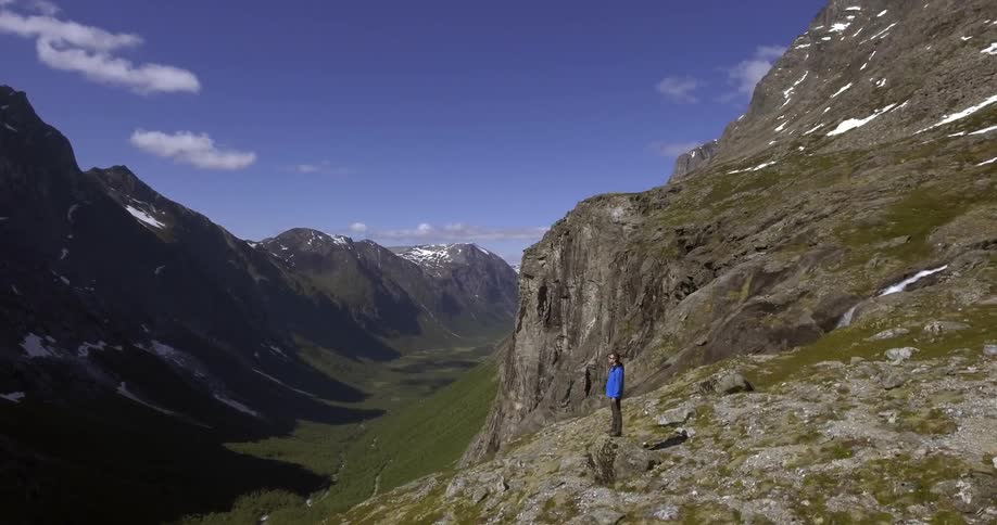 A person is standing on a rock near a cliff
