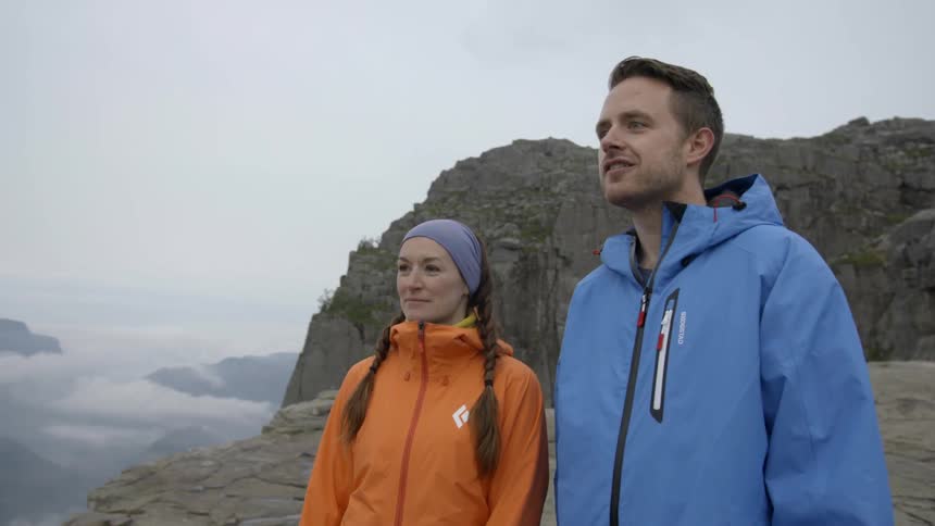 A man and women look over the edge of a cliff