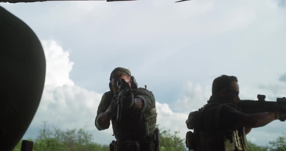 Two military men are walking outside with guns