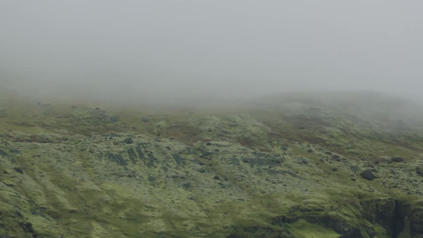 A hill with rocks with fog in the background