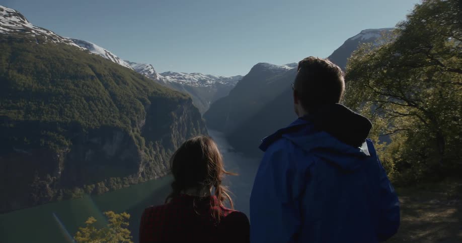 A man and women look at a view from top of a mountain