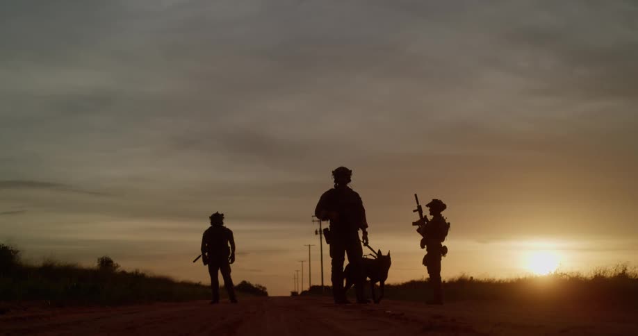 Three military men are standing outdoors at dusk