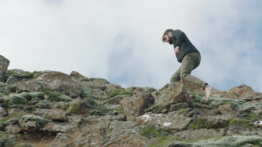 A man is hiking up a rocky hill