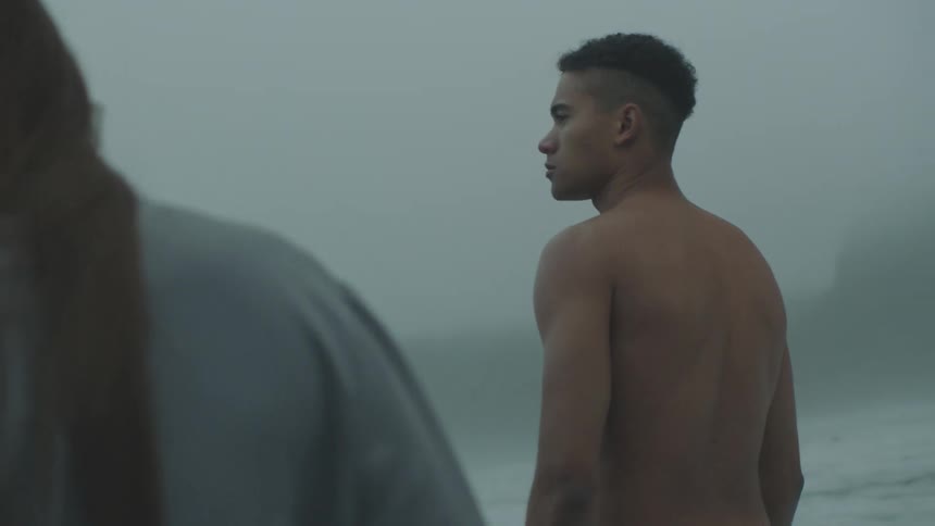 Teenage boy walks down beach beside another person on a foggy misty day