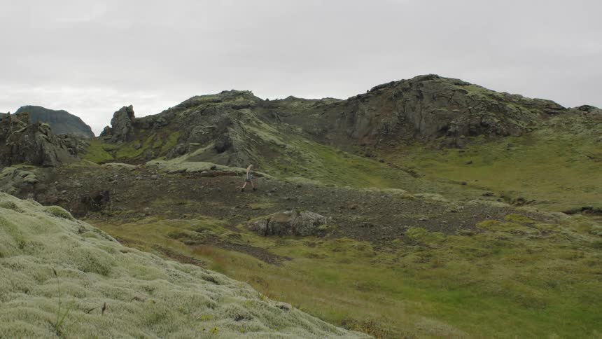 Young woman walking on the moss covered hills on the highland