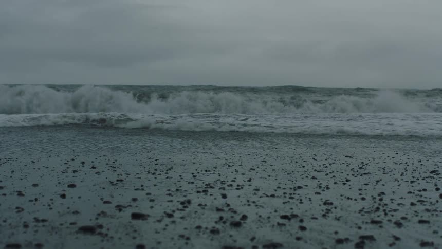 Ocean waves crashing on the shoreline of a beach on an overcast day