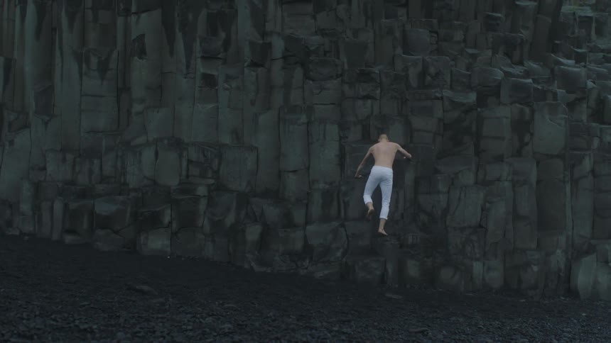 A man with white pants climbing a rocky cliff