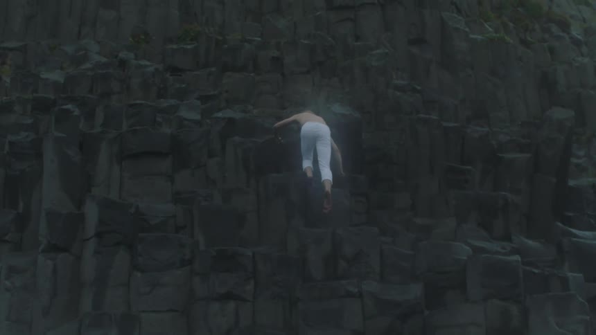 A man climbs up the side of a cliff