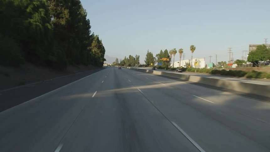 A highway with signs and vehicles with the sky and clouds in the background