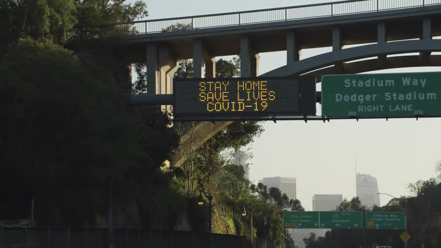 Covid19 warning signs on the highway near the city at sunrise