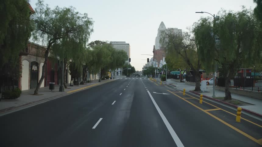 An empty city street lined with buildings and a few cars parked in a lot