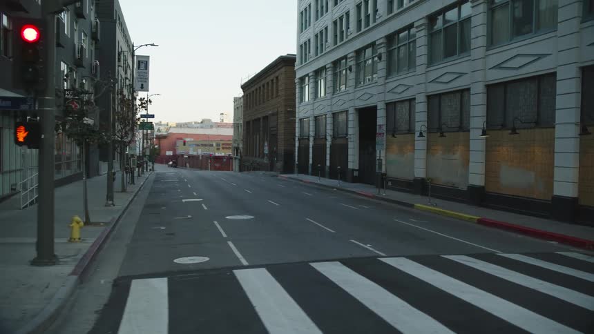 A rolling shot of a city street with boarded up windows