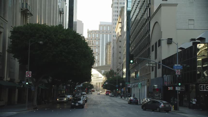 View of downtown area from the street level with traffic buildings trees traffic lights and signs during the day