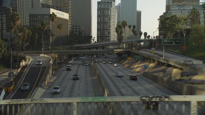 Traffic moves under several overpasses on a freeway in a metropolis during the day
