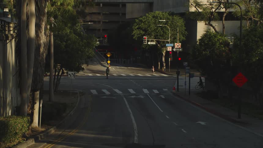Pedestrians and vehicles travel across an intersection in a metropolis during the day