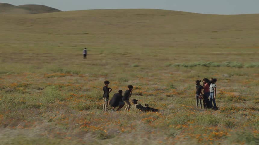Family group taking pictures on a trip on the grass near the hills