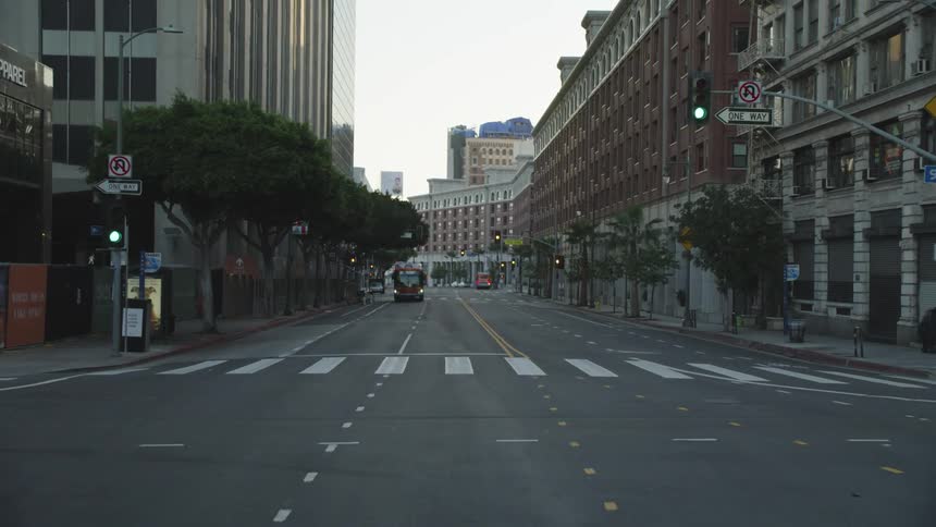 A bus drives down a quiet city street lined with buildings
