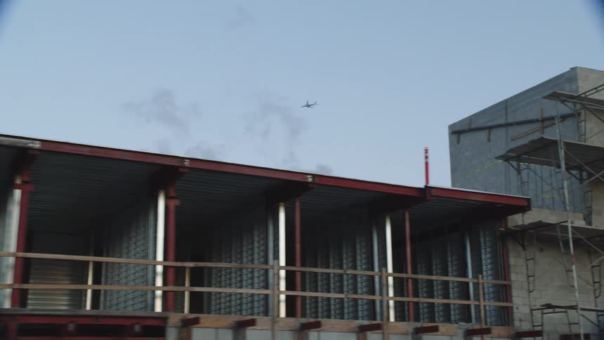 A city with buildings and trees with an airplane in the sky in the background