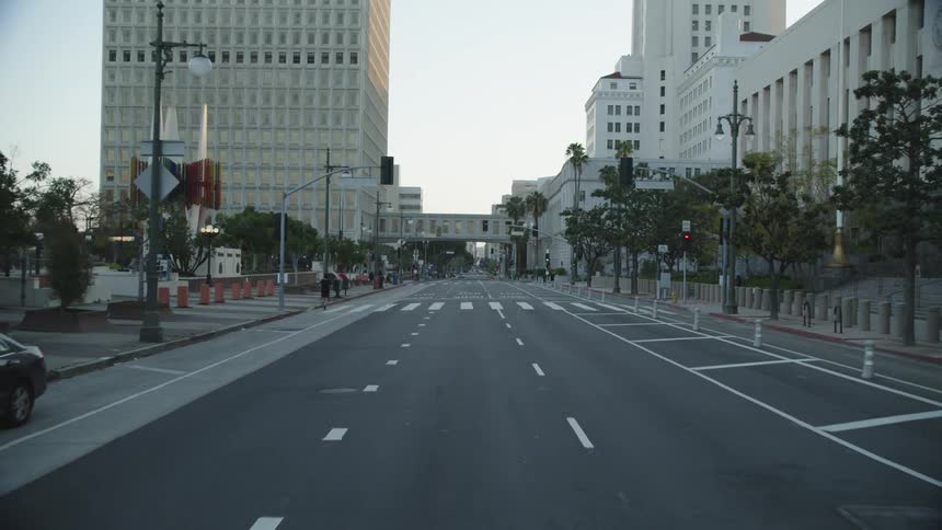 A city street with buildings a car parked and one person running on it