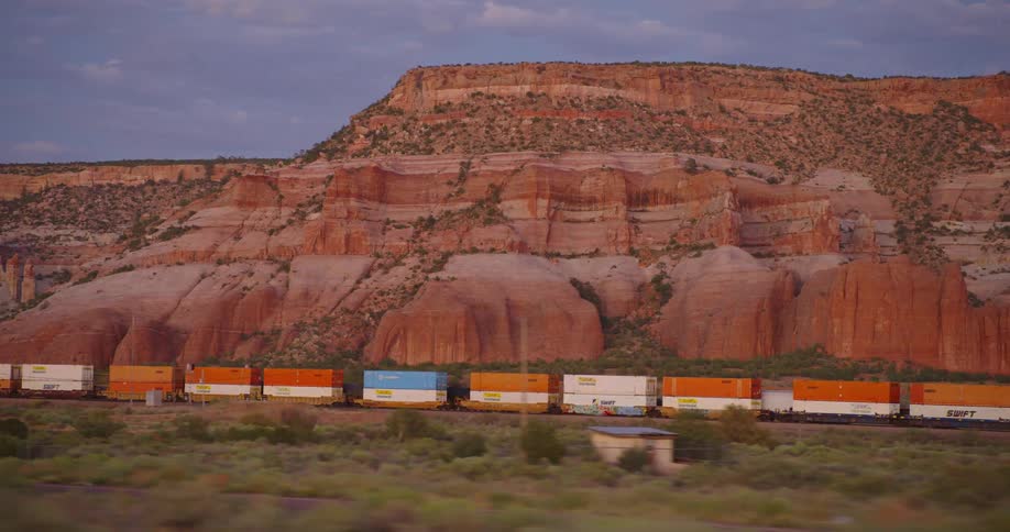 Shipping containers on a train drive past a canyon