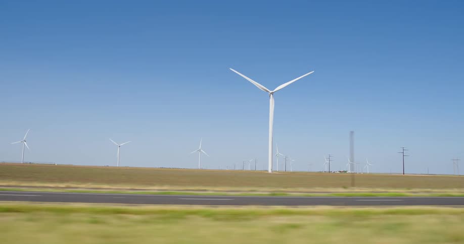 Driving by turbines on a wind farm in the country